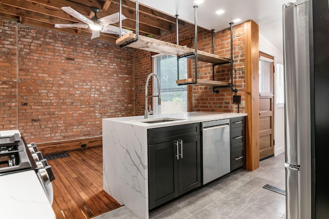 867-871 Delaware Ave, Columbus, OH 43215 - kitchen with appliances with stainless steel finishes, open shelves, a ceiling fan, brick wall, and light stone counters