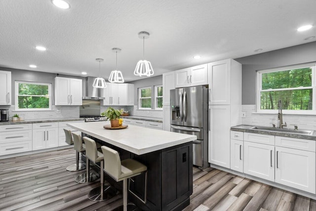 10382 Wright Rd NW, Canal Winchester, OH 43110 - kitchen featuring stainless steel refrigerator with ice dispenser, wall chimney exhaust hood, decorative backsplash, a breakfast bar area, and a kitchen island