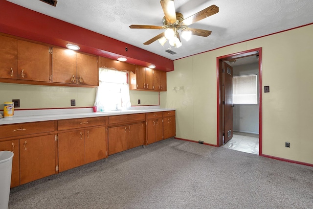 412 E Mill St, Circleville, OH 43113 - kitchen with ceiling fan, brown cabinetry, light countertops, light colored carpet, and a textured ceiling
