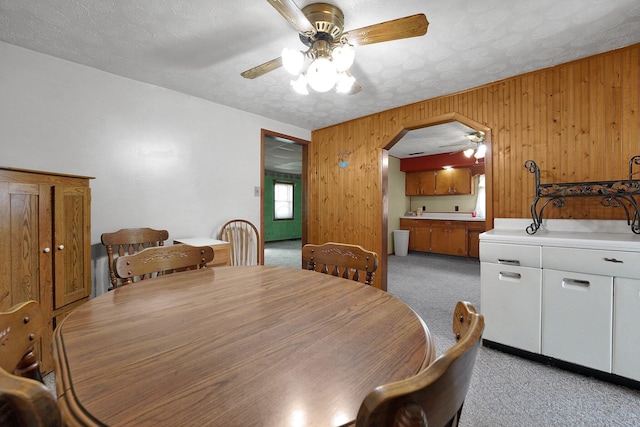 412 E Mill St, Circleville, OH 43113 - dining area with light carpet, a ceiling fan, wood walls, and arched walkways