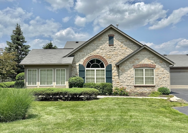 6608 Lakeview Cir, Canal Winchester, OH 43110 - french country home featuring stone siding, a front yard, driveway, a shingled roof, and an attached garage