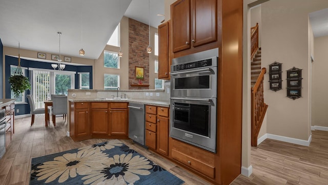 6229 Janes Way, Hilliard, OH 43026 - kitchen featuring appliances with stainless steel finishes, a peninsula, brown cabinetry, high vaulted ceiling, and light wood finished floors