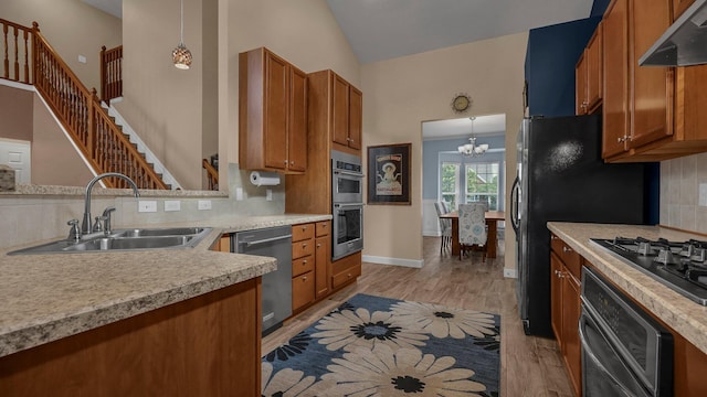6229 Janes Way, Hilliard, OH 43026 - kitchen with appliances with stainless steel finishes, brown cabinetry, under cabinet range hood, a chandelier, and tasteful backsplash