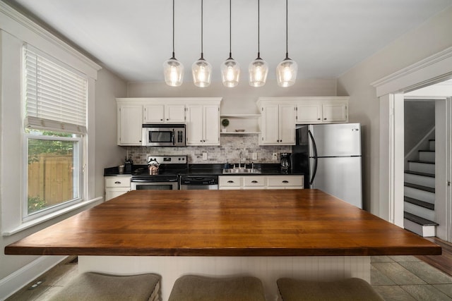 336 E Kossuth St, Columbus, OH 43206 - kitchen featuring appliances with stainless steel finishes, wooden counters, a center island, decorative backsplash, and white cabinets