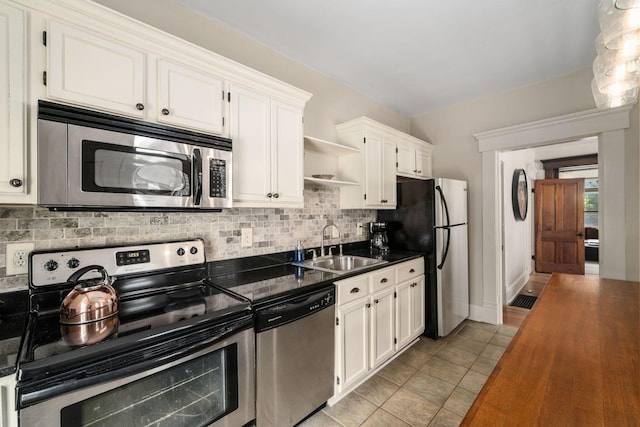 336 E Kossuth St, Columbus, OH 43206 - kitchen with stainless steel appliances, dark countertops, open shelves, tasteful backsplash, and white cabinetry