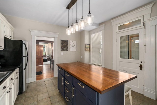 336 E Kossuth St, Columbus, OH 43206 - kitchen featuring wooden counters, blue cabinets, white cabinets, light tile patterned floors, and pendant lighting