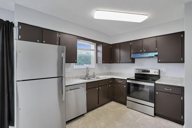7607-7609 Penwood Pl, Columbus, OH 43235 - kitchen with stainless steel appliances, under cabinet range hood, light countertops, dark brown cabinetry, and a textured ceiling