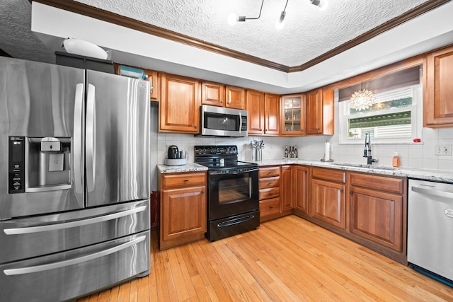 505 Tresham Rd, Columbus, OH 43230 - kitchen featuring appliances with stainless steel finishes, ornamental molding, brown cabinetry, light wood-type flooring, and tasteful backsplash