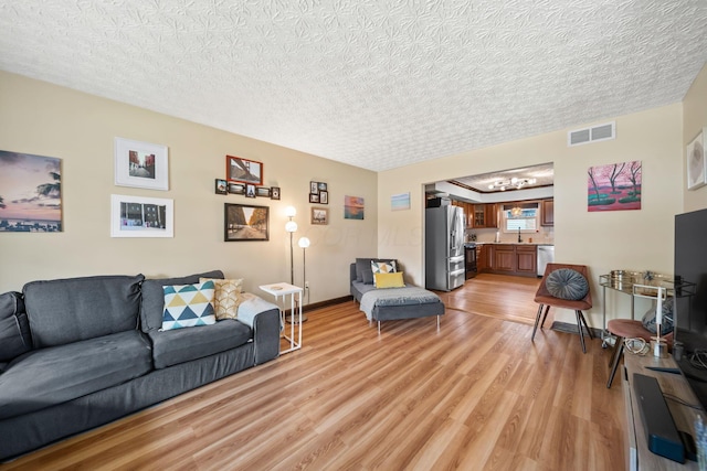505 Tresham Rd, Columbus, OH 43230 - living area featuring light wood-style floors, a chandelier, and a textured ceiling