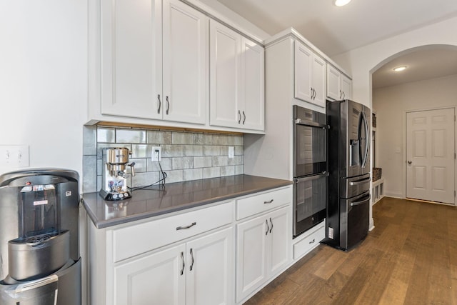 3622 Switchgrass Ct, Hilliard, OH 43026 - kitchen featuring stainless steel fridge with ice dispenser, arched walkways, dark countertops, dark wood-style flooring, and tasteful backsplash
