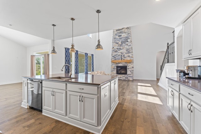 3622 Switchgrass Ct, Hilliard, OH 43026 - kitchen with dishwasher, dark countertops, lofted ceiling, a stone fireplace, and an island with sink