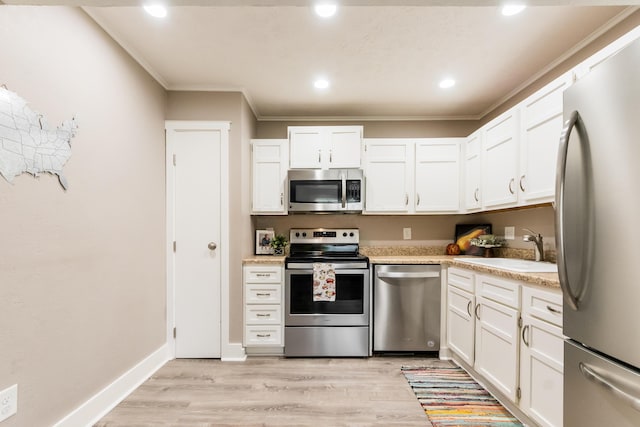 7831 Meadowhaven Blvd Unit 73, Columbus, OH 43235 - kitchen featuring appliances with stainless steel finishes, crown molding, light countertops, white cabinets, and light wood-style flooring