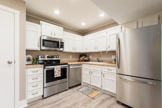 7831 Meadowhaven Blvd Unit 73, Columbus, OH 43235 - kitchen featuring appliances with stainless steel finishes, ornamental molding, light wood-style flooring, light countertops, and white cabinetry