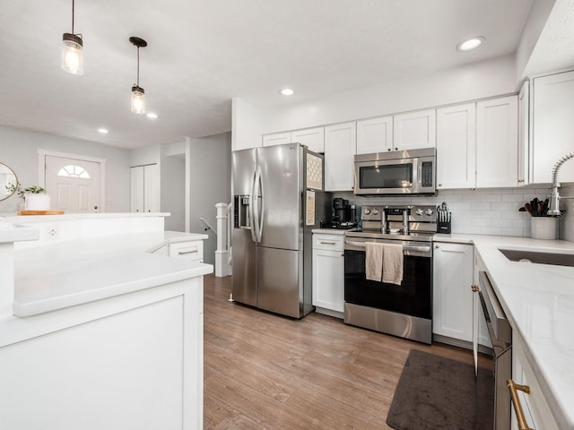 5611 Donnally Ct, Dublin, OH 43016 - kitchen with appliances with stainless steel finishes, white cabinetry, backsplash, light wood-style floors, and decorative light fixtures