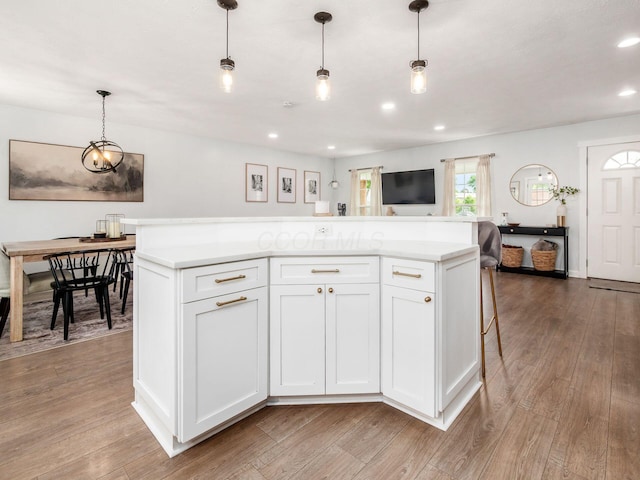 5611 Donnally Ct, Dublin, OH 43016 - kitchen featuring light countertops, light wood finished floors, white cabinets, decorative light fixtures, and a center island
