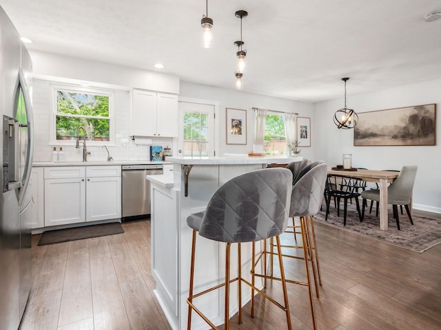 5611 Donnally Ct, Dublin, OH 43016 - kitchen featuring appliances with stainless steel finishes, hardwood / wood-style flooring, a kitchen bar, a kitchen island, and recessed lighting