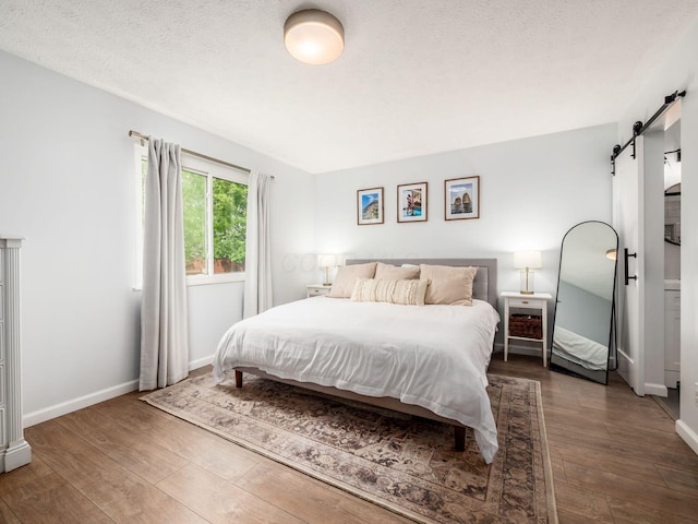5611 Donnally Ct, Dublin, OH 43016 - bedroom featuring a barn door, wood-type flooring, and a textured ceiling