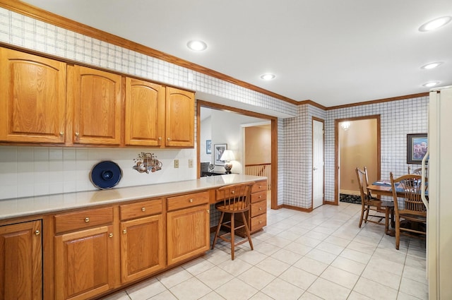 3175 Dartford Trce, Dublin, OH 43017 - kitchen with ornamental molding, wallpapered walls, built in desk, light countertops, and brown cabinets