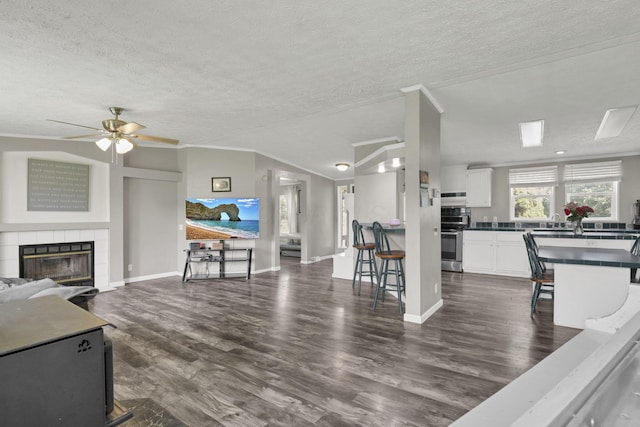 6471 Graham Rd, Mount Vernon, OH 43050 - living area with a textured ceiling, dark wood-style floors, a ceiling fan, a tile fireplace, and crown molding