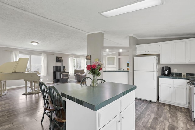 6471 Graham Rd, Mount Vernon, OH 43050 - kitchen with freestanding refrigerator, tile countertops, a wood stove, white cabinetry, and ornamental molding