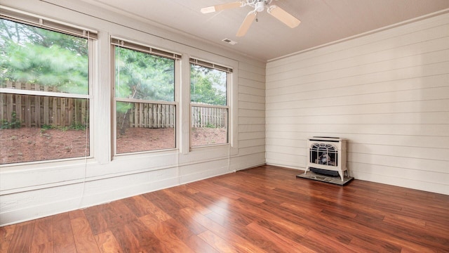 74 Stonington Cir, Newark, OH 43055 - unfurnished room with a wood stove, heating unit, wood finished floors, a ceiling fan, and wood walls