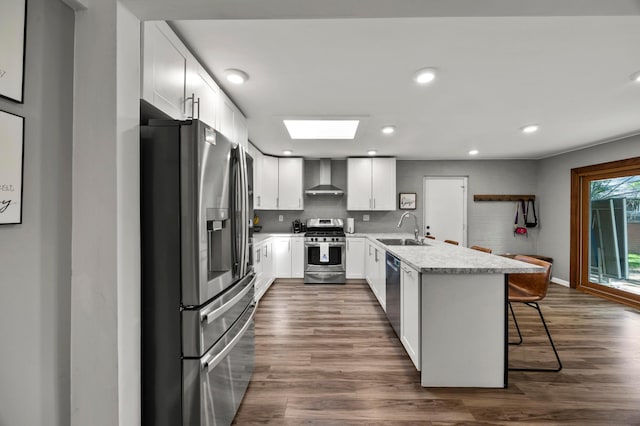 298 Flint Ridge Dr, Columbus, OH 43230 - kitchen with stainless steel appliances, wall chimney range hood, a peninsula, a breakfast bar area, and light countertops
