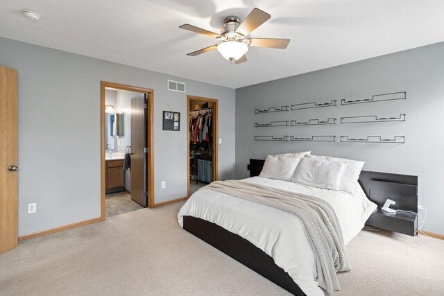 486 Ruffin Dr, Galloway, OH 43119 - bedroom featuring light carpet, a walk in closet, a closet, ensuite bathroom, and a ceiling fan
