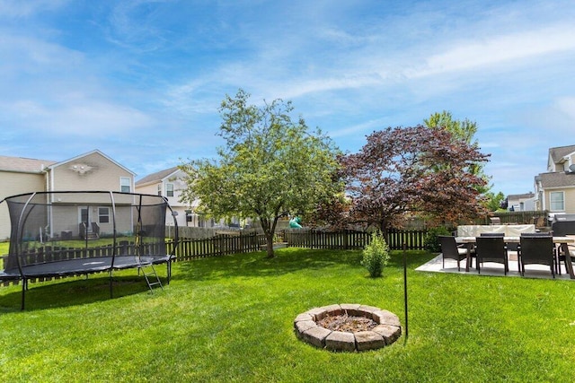 486 Ruffin Dr, Galloway, OH 43119 - fenced backyard with a trampoline, a patio area, an outdoor fire pit, and a residential view