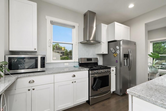 497 E Kossuth St, Columbus, OH 43206 - kitchen featuring stainless steel appliances, wall chimney exhaust hood, dark wood-type flooring, backsplash, and white cabinets