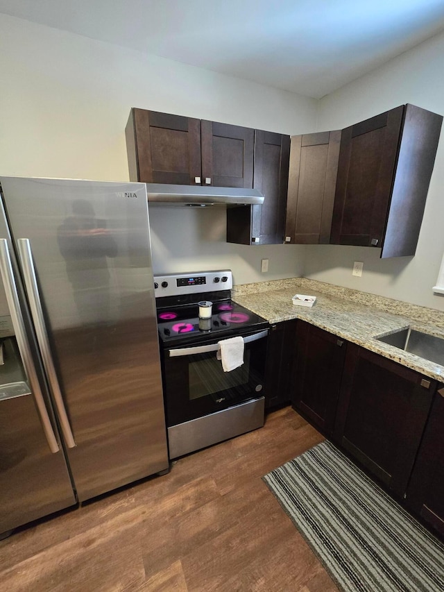 2205-2207 Sullivant Ave, Columbus, OH 43223 - kitchen featuring appliances with stainless steel finishes, under cabinet range hood, wood finished floors, light stone counters, and dark brown cabinetry
