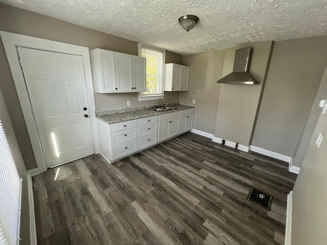 1514-1516 E 26th Ave, Columbus, OH 43211 - kitchen with wall chimney exhaust hood, white cabinetry, dark wood finished floors, a textured ceiling, and light stone countertops