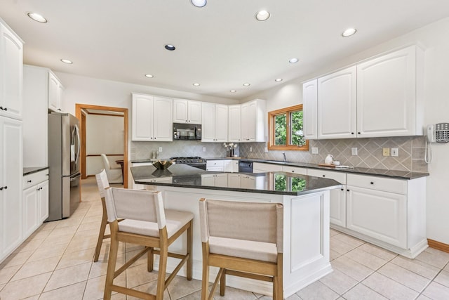 1318 Retreat Ln, New Albany, OH 43054 - kitchen with black appliances, a breakfast bar area, recessed lighting, backsplash, and light tile patterned flooring