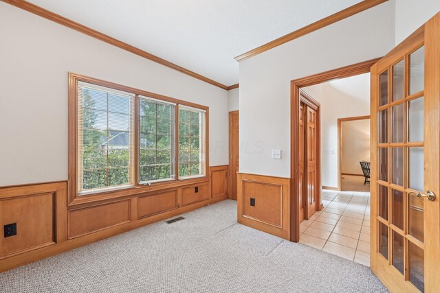 1318 Retreat Ln, New Albany, OH 43054 - empty room with wainscoting, crown molding, light colored carpet, light tile patterned floors, and french doors