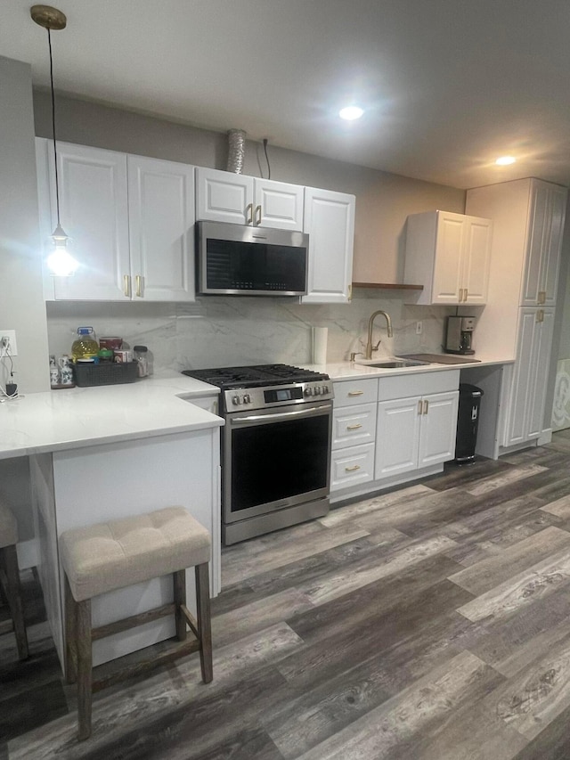 3107 Huntington Dr, Columbus, OH 43207 - kitchen with stainless steel appliances, white cabinetry, dark wood-type flooring, light countertops, and tasteful backsplash