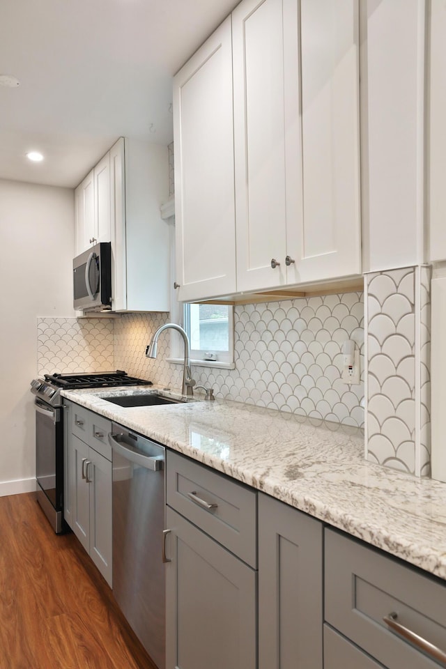 595 Brookside Dr, Columbus, OH 43209 - kitchen with stainless steel appliances, gray cabinetry, wood finished floors, decorative backsplash, and white cabinetry