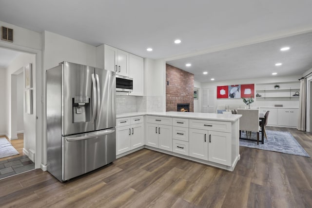 4289 Shelbourne Ln, Columbus, OH 43220 - kitchen with stainless steel appliances, a peninsula, white cabinetry, dark wood finished floors, and light countertops