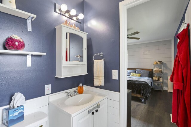 372 Sturbridge Rd, Columbus, OH 43228 - bathroom featuring vanity, wood finished floors, ceiling fan, connected bathroom, and wooden walls