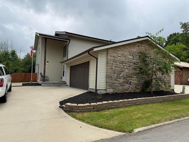 412 Old Stone Ct, Mansfield, OH 44904 - view of side of home featuring concrete driveway, an attached garage, and stone siding