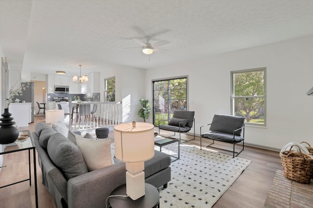 8139 Storrow Dr, Westerville, OH 43081 - living area with a ceiling fan, a chandelier, light wood-style floors, and a textured ceiling