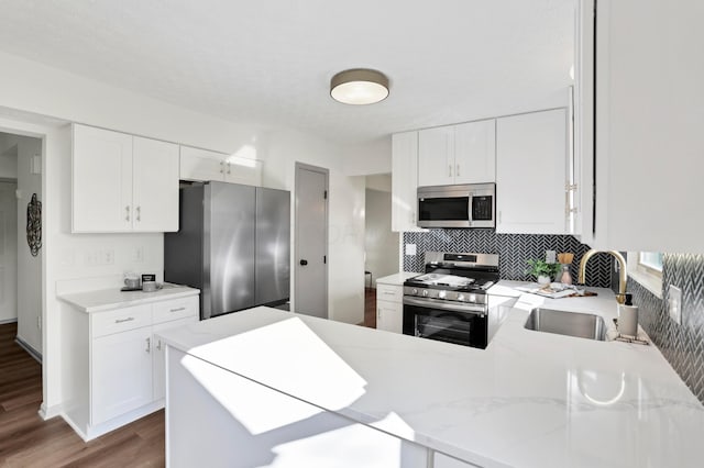 8139 Storrow Dr, Westerville, OH 43081 - kitchen with appliances with stainless steel finishes, tasteful backsplash, a peninsula, wood finished floors, and white cabinetry