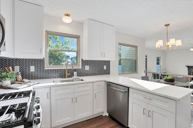 8139 Storrow Dr, Westerville, OH 43081 - kitchen featuring stainless steel appliances, a peninsula, a chandelier, decorative backsplash, and light countertops