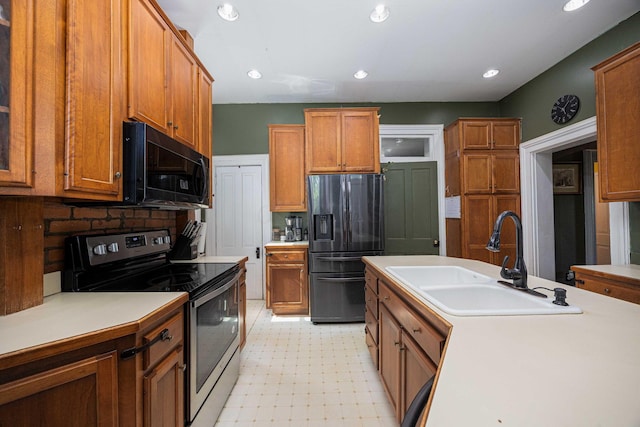 1871 Galloway Rd, Galloway, OH 43119 - kitchen with stainless steel electric range, refrigerator with ice dispenser, black microwave, brown cabinets, and light floors