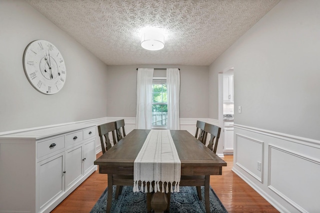 712 Suntree Dr, Westerville, OH 43081 - dining room with a textured ceiling, light wood-type flooring, a wainscoted wall, and a decorative wall
