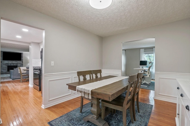712 Suntree Dr, Westerville, OH 43081 - dining space with light wood-type flooring, a fireplace, a wainscoted wall, and a decorative wall