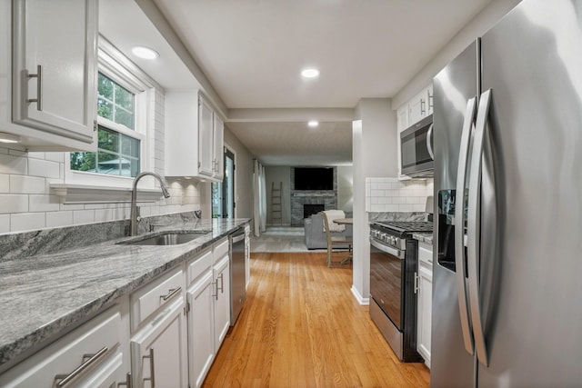 712 Suntree Dr, Westerville, OH 43081 - kitchen featuring appliances with stainless steel finishes, white cabinets, a fireplace, recessed lighting, and light wood finished floors