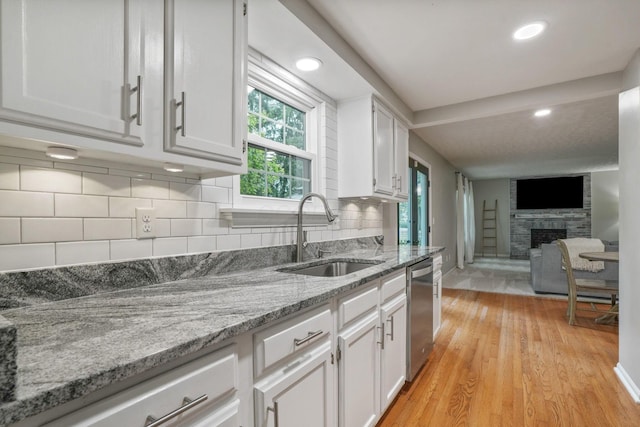 712 Suntree Dr, Westerville, OH 43081 - kitchen with healthy amount of natural light, white cabinets, stainless steel dishwasher, a fireplace, and recessed lighting