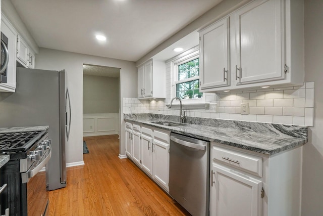 712 Suntree Dr, Westerville, OH 43081 - kitchen with appliances with stainless steel finishes, light wood finished floors, white cabinetry, stone counters, and backsplash