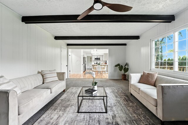 1360 Langston Dr, Columbus, OH 43220 - living room featuring a textured ceiling, dark carpet, beam ceiling, ceiling fan, and wooden walls