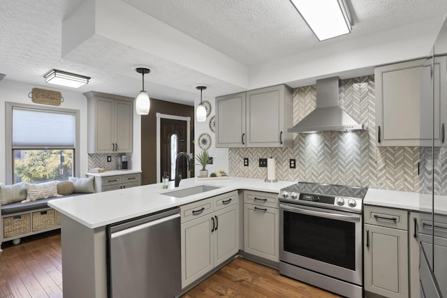 215 Barb Ct, Heath, OH 43056 - kitchen featuring stainless steel appliances, wall chimney range hood, gray cabinetry, a textured ceiling, and a peninsula