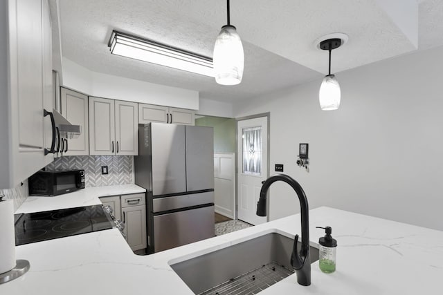 215 Barb Ct, Heath, OH 43056 - kitchen with freestanding refrigerator, gray cabinetry, light stone counters, backsplash, and decorative light fixtures